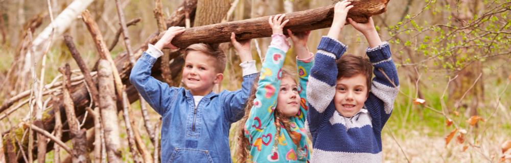 Børn bærer træstamme i fællesskab